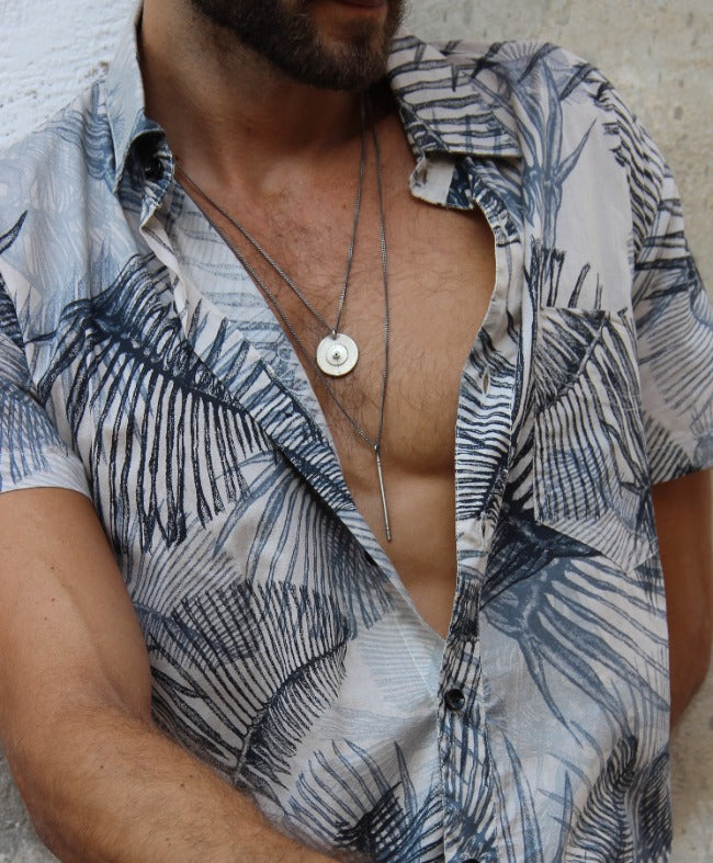 A silver necklace with a pendant resembling a stick