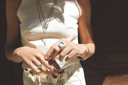 A silver necklace with a pendant featuring a circular design and a chain that ends in a pendant loop.