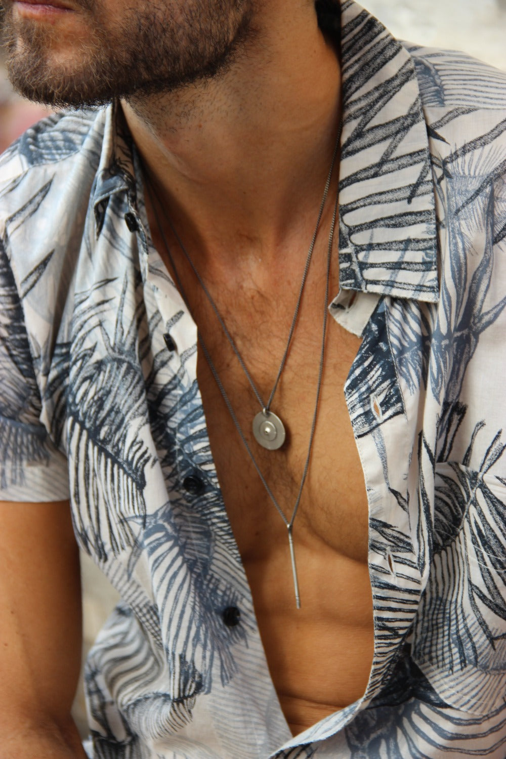 A silver necklace with a pendant resembling a stick
