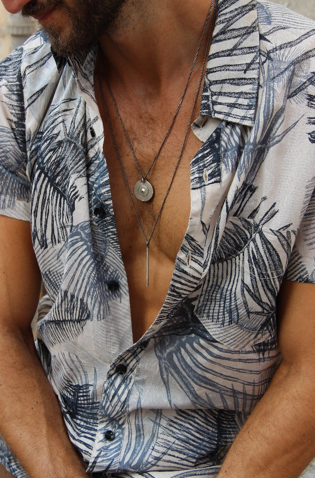 A silver necklace with a pendant resembling a stick