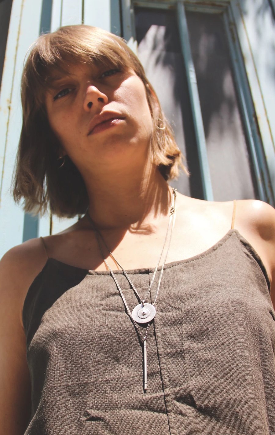 A silver necklace with a pendant resembling a stick
