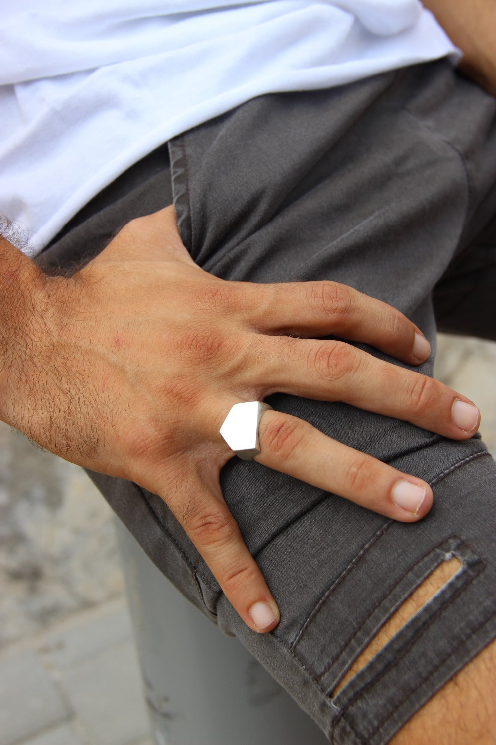 A silver ring with a geometric cutout design on the top part, with a matte finish.
