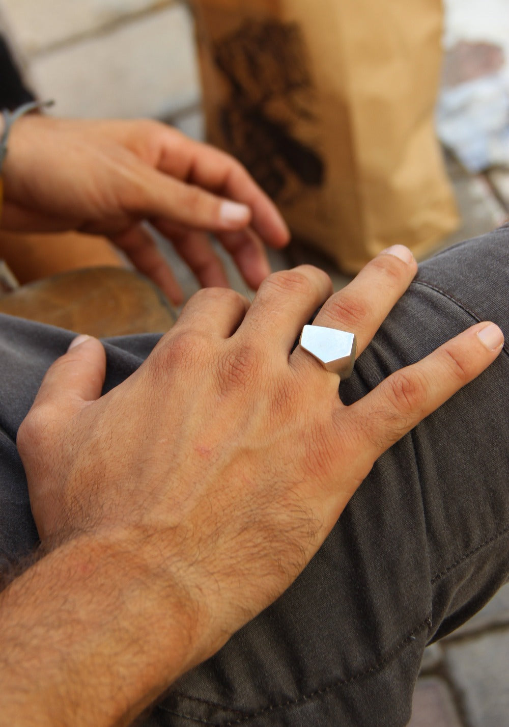 A silver ring with a geometric cutout design on the top part, with a matte finish.