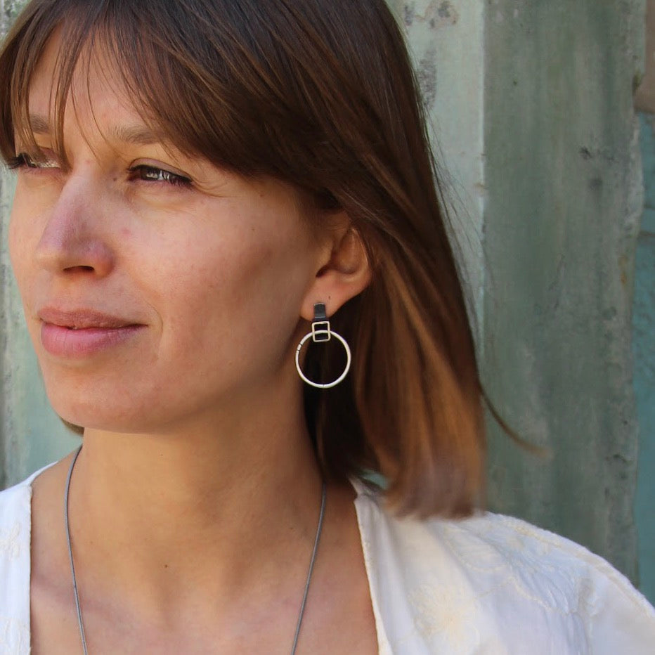 A pair of silver oxidized and brushed finish earrings with a geometric design