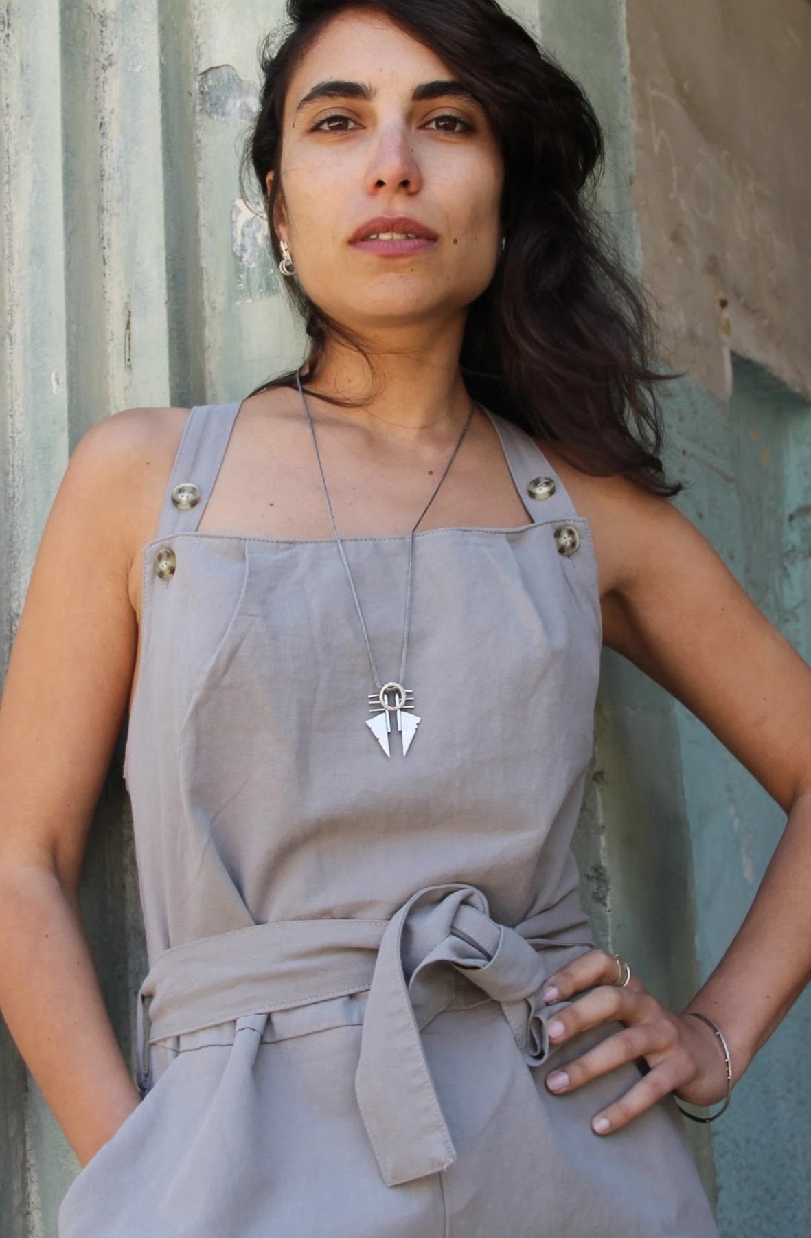 A sterling silver necklace with a pendant featuring two triangles and a circular ornament, with a brushed and oxidized finish.