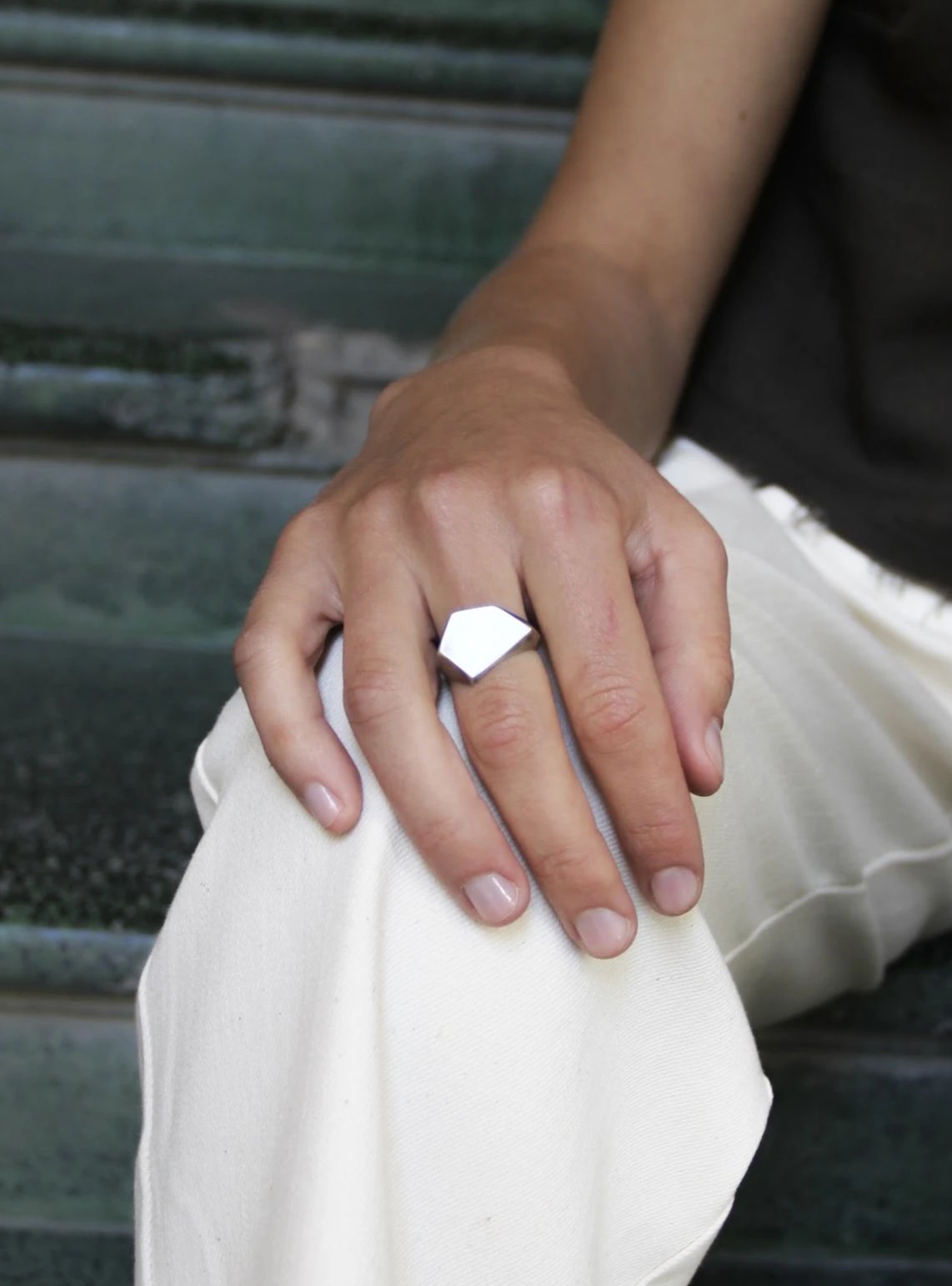 A silver ring with a geometric cutout design on the top part, with a matte finish.