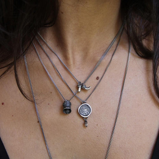A silver necklace with a pendant featuring an ancient Hindu coin design with the figure of Hanuman- Monkey god, accompanied by two tiny labradorite stones.