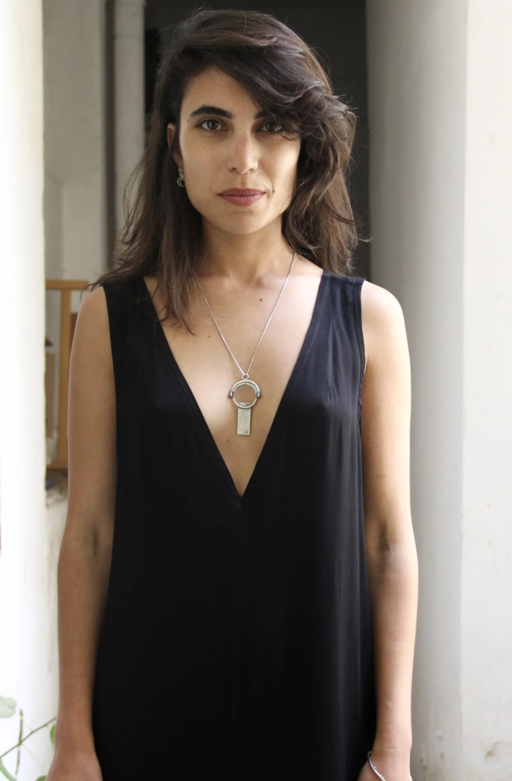 A sterling silver necklace with a magnifying glass pendant and a cross on the chain.