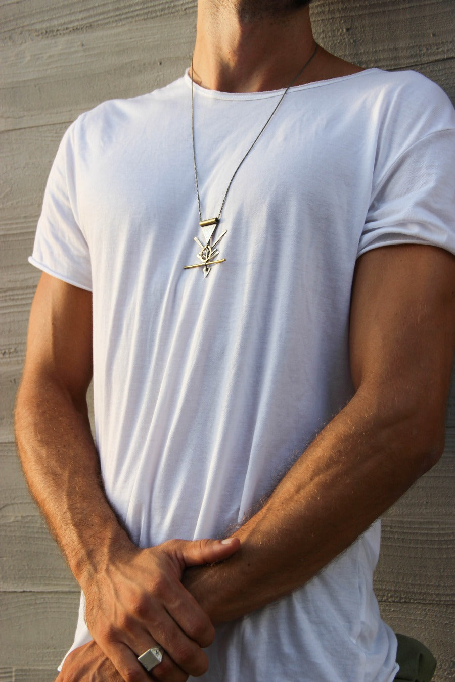 A silver and brass necklace with a geometric pendant, featuring a chain and a series of geometric shaped pendants attached to it.