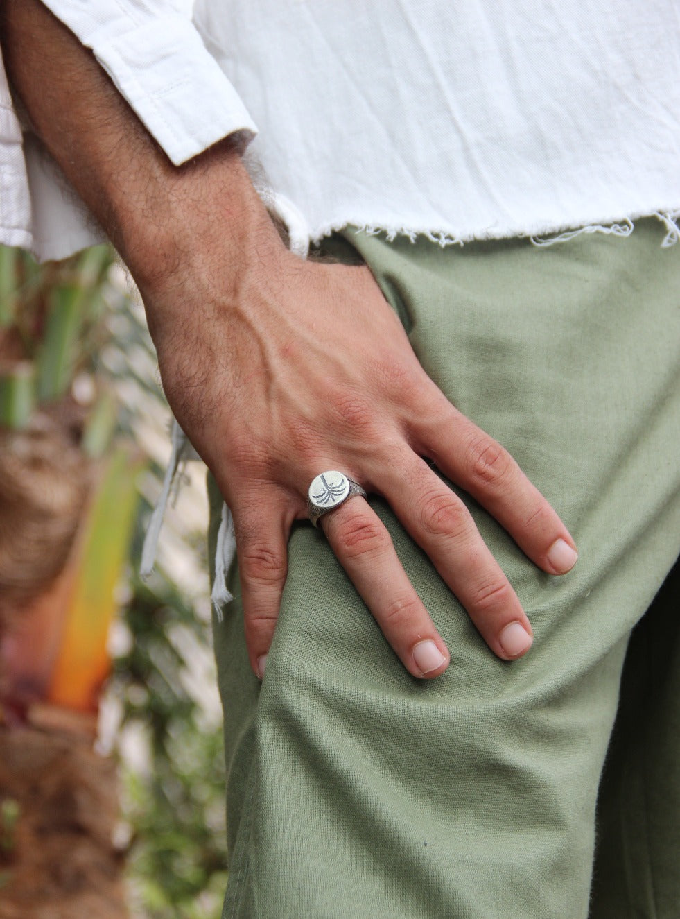A silver ring with a brushed finish and a palm tree design on the top, signet-style.