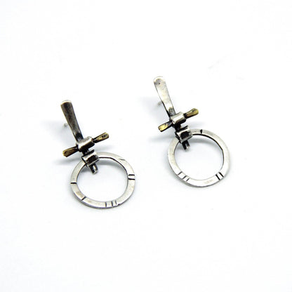 A pair of silver and brass earrings with a geometric design, displayed against a white background.