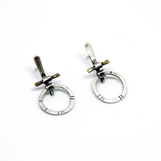 A pair of silver and brass earrings with a geometric design, displayed against a white background.