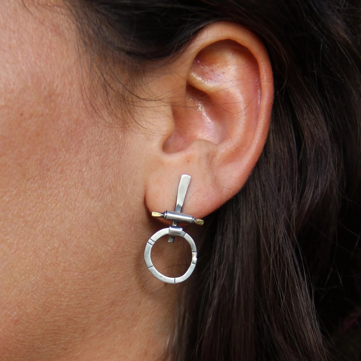 A pair of silver and brass earrings with a geometric design