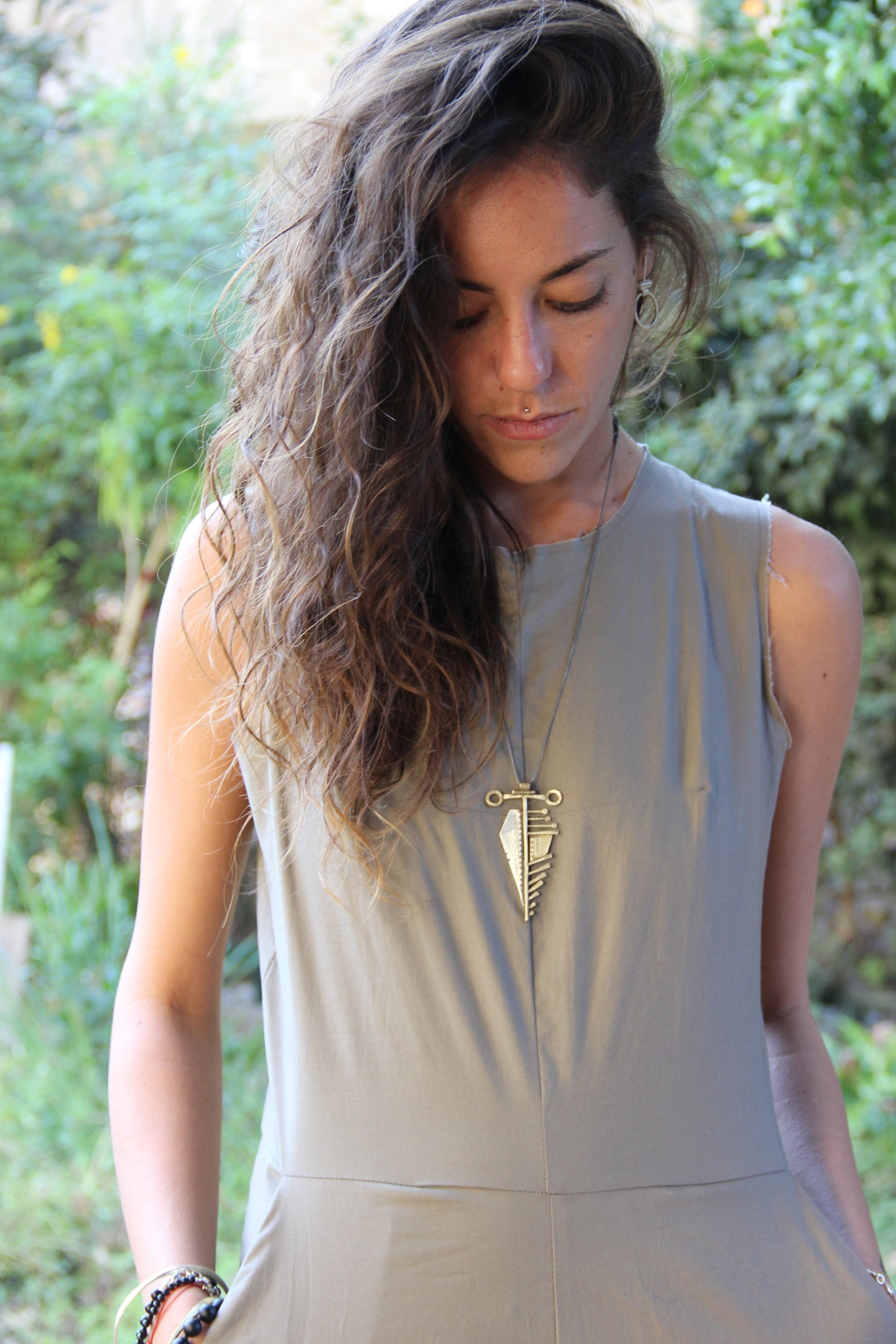 A sterling silver and brass necklace with a pendant featuring a design that resembles an arrow, attached to a chain.
