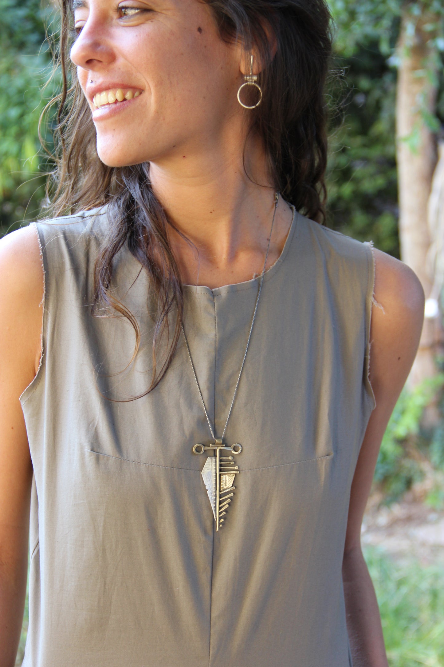 A sterling silver and brass necklace with a pendant featuring a design that resembles an arrow, attached to a chain.