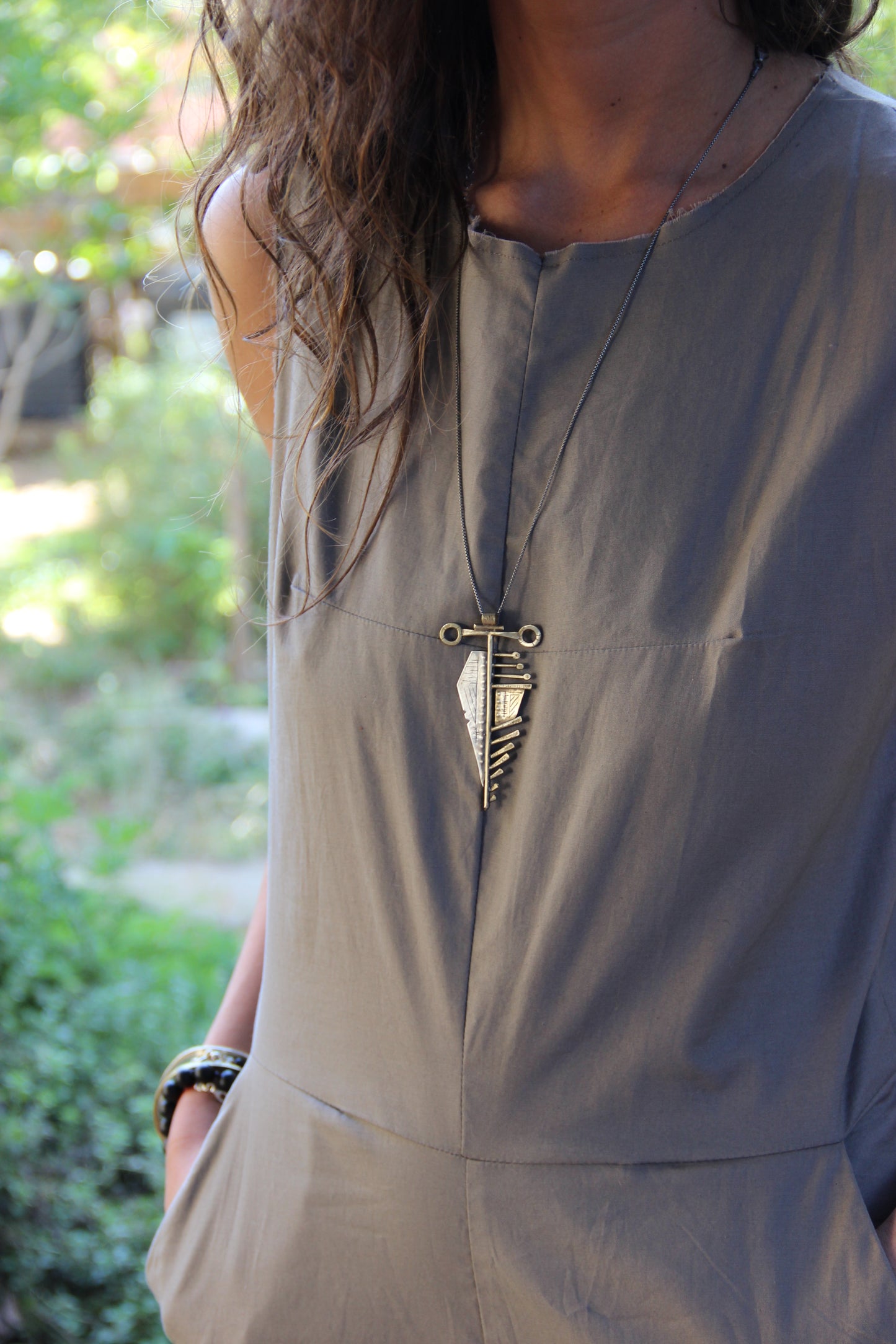 A sterling silver and brass necklace with a pendant featuring a design that resembles an arrow, attached to a chain.