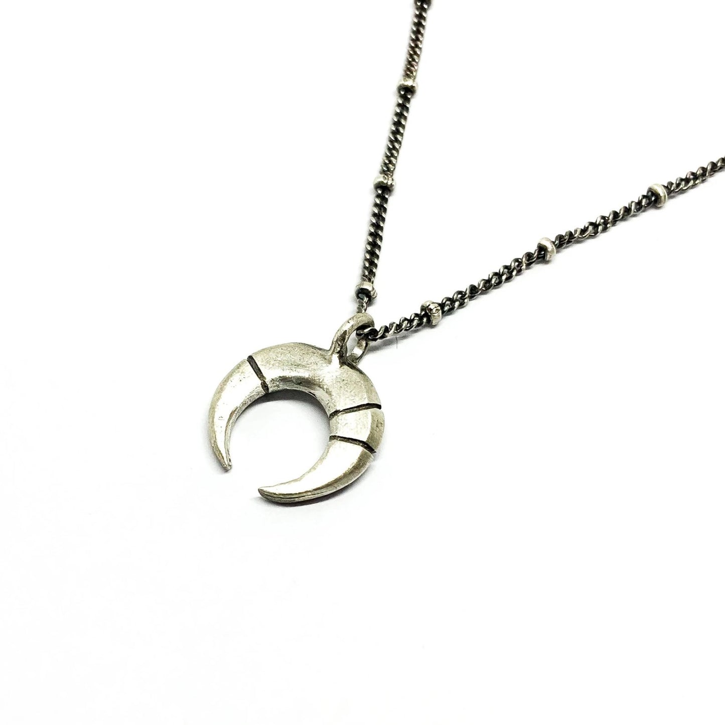 A silver necklace with a crescent-moon pendant and chain.