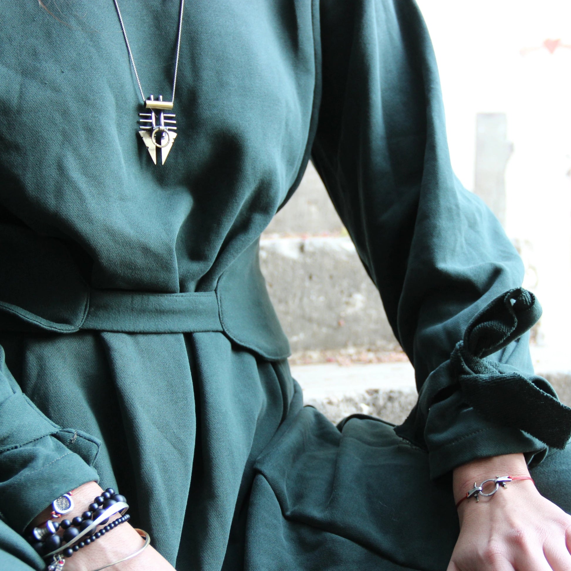A silver and brass pendant necklace with a chain, featuring a warrior or praying mantis design.