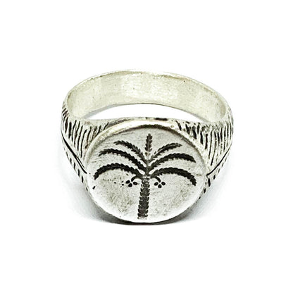 A silver ring with a brushed finish and a palm tree design on the top, signet-style.