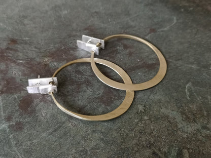 A pair of silver and brass hoop earrings with a brushed finish and a geometric design