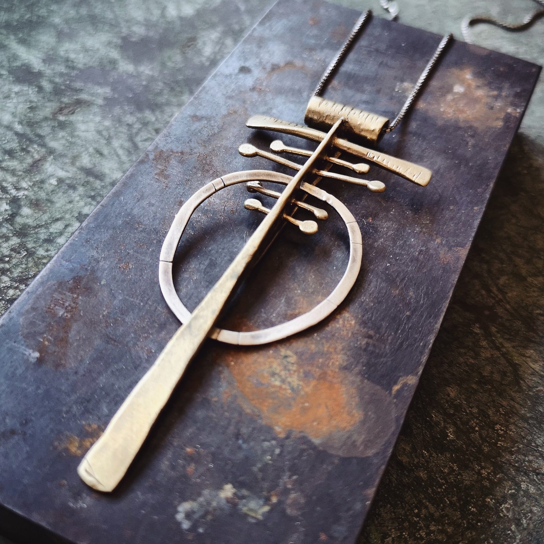A silver and brass necklace with a geometric pendant