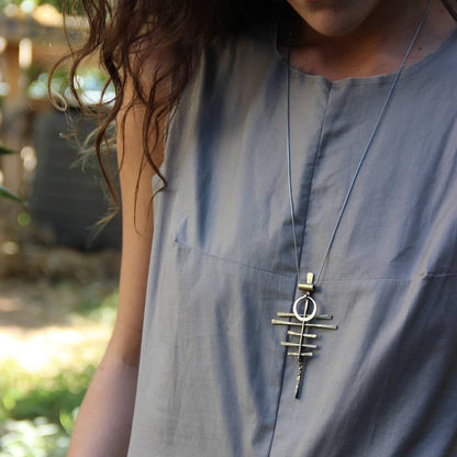 A silver-colored necklace with a pendant featuring a series of parallel lines and a circular ring