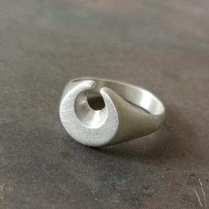 A silver ring featuring a brushed finish, handcrafted in the shape of a moon.