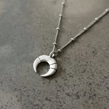 A silver necklace with a crescent-moon pendant and chain.