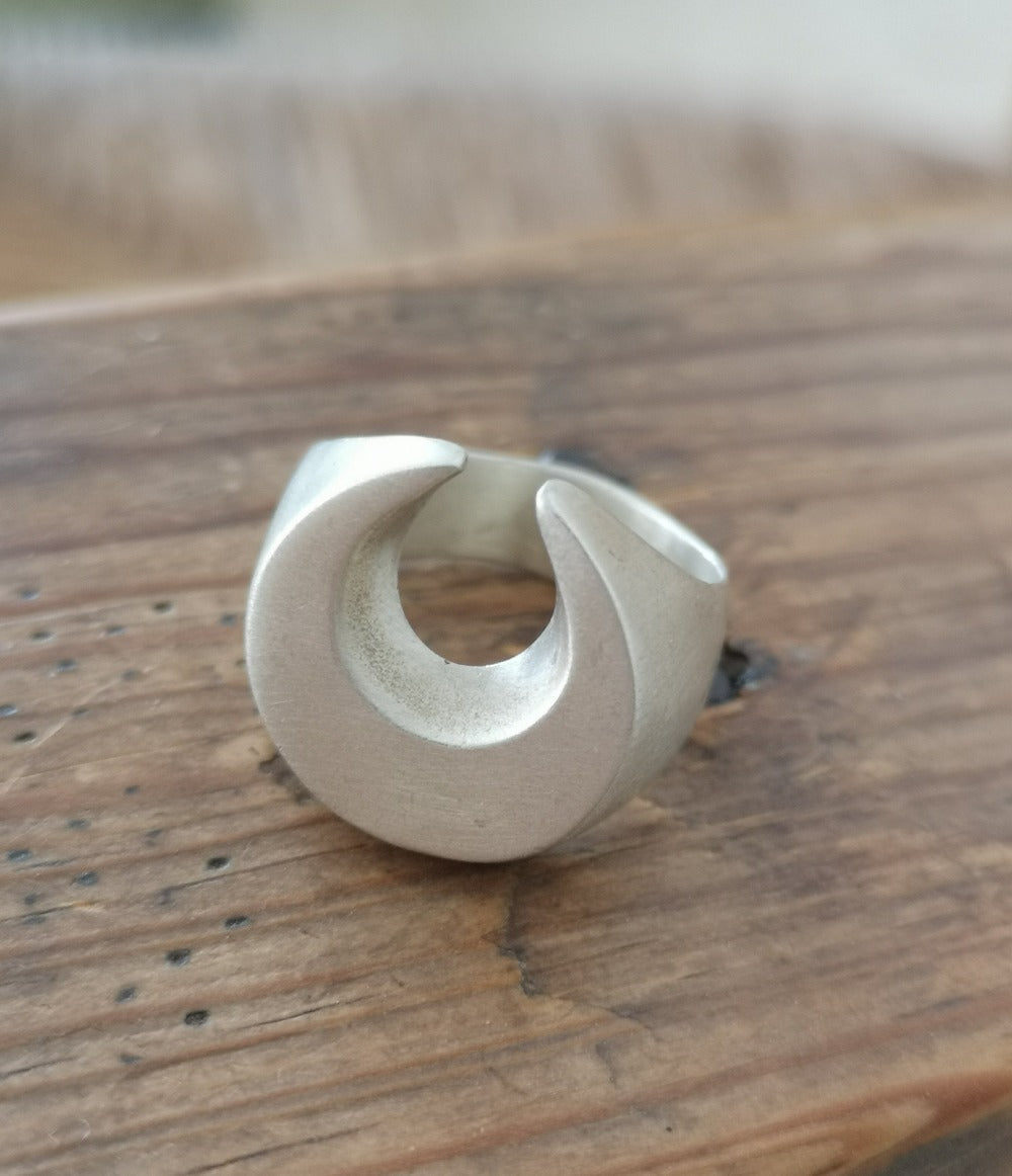 A silver signet ring with a brushed finish, featuring a crescent moon design.
