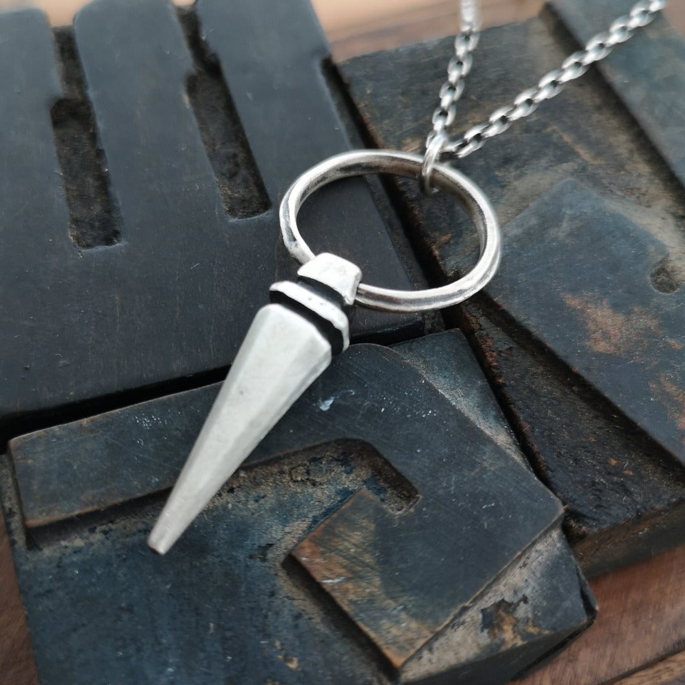 A sterling silver pendulum necklace with a brushed finish and a chain loop at the top. The pendulum is large and has a smooth, polished appearance.