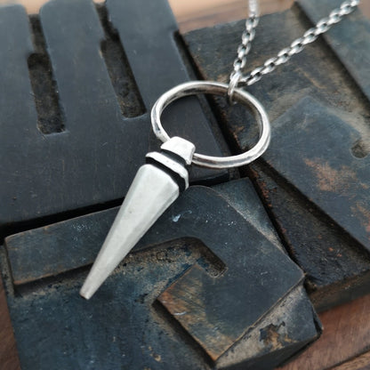 A sterling silver pendulum necklace with a brushed finish and a chain loop at the top. The pendulum is large and has a smooth, polished appearance.