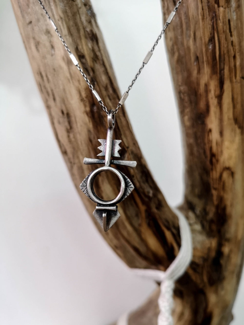 A silver necklace with a geometric-patterned pendant, featuring a combination of Morrocan and Mexican inspiration.