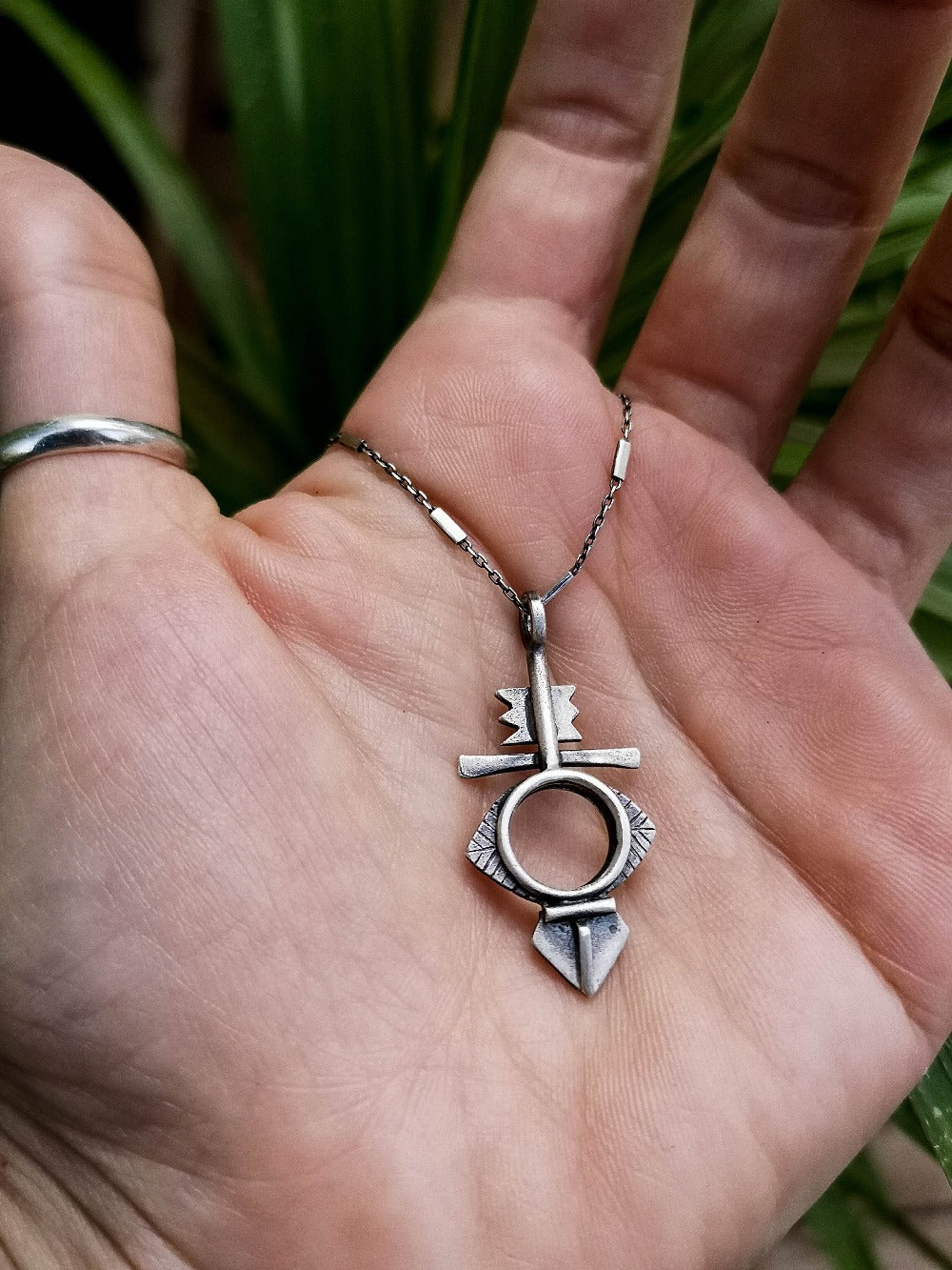 A silver necklace with a geometric-patterned pendant, featuring a combination of Morrocan and Mexican inspiration.