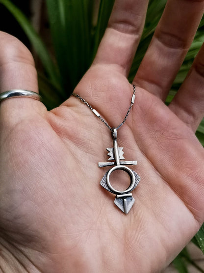 A silver necklace with a geometric-patterned pendant, featuring a combination of Morrocan and Mexican inspiration.
