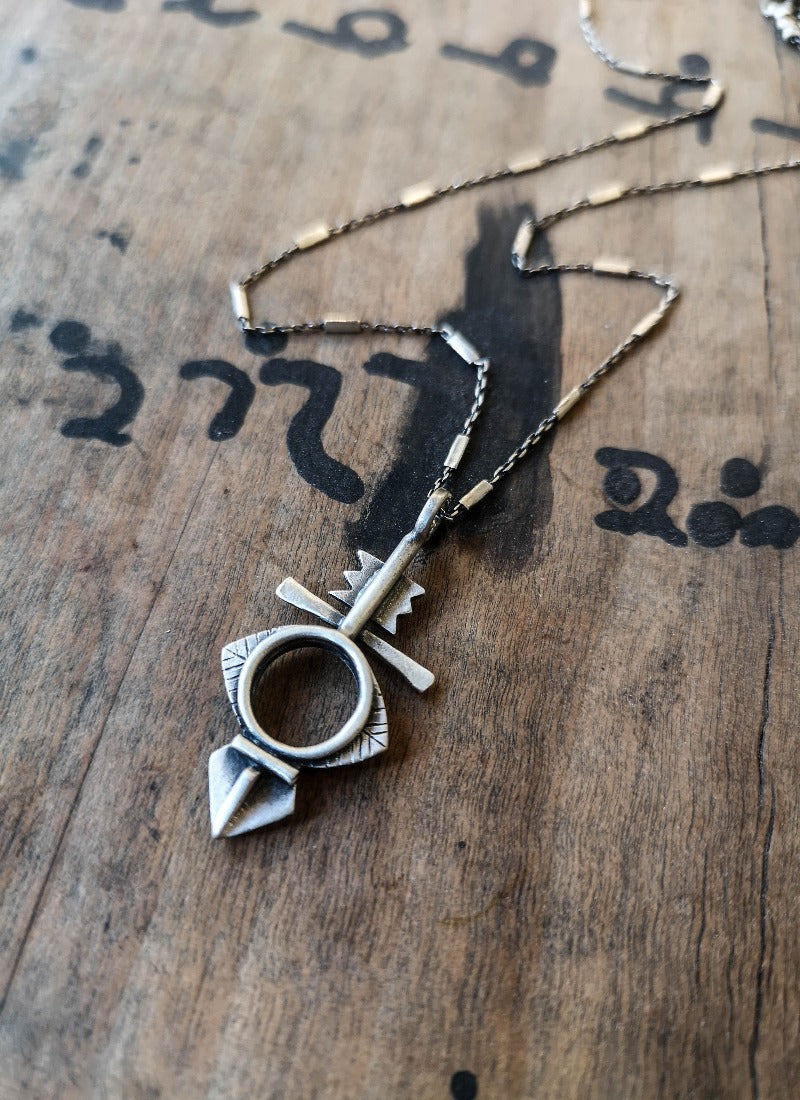 A silver necklace with a geometric-patterned pendant, featuring a combination of Morrocan and Mexican inspiration.