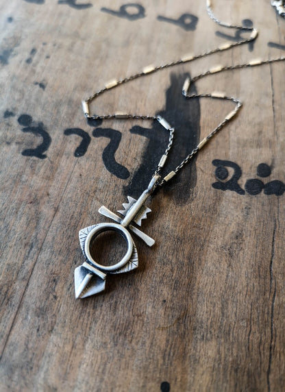 A silver necklace with a geometric-patterned pendant, featuring a combination of Morrocan and Mexican inspiration.