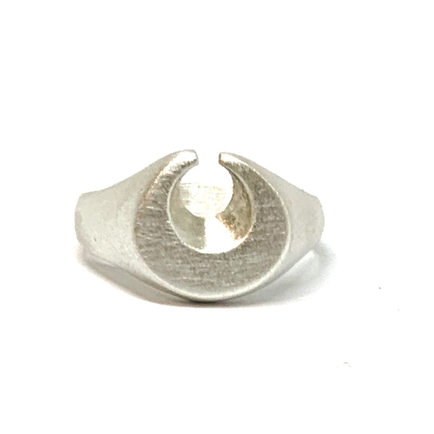 A silver ring featuring a brushed finish, handcrafted in the shape of a moon.