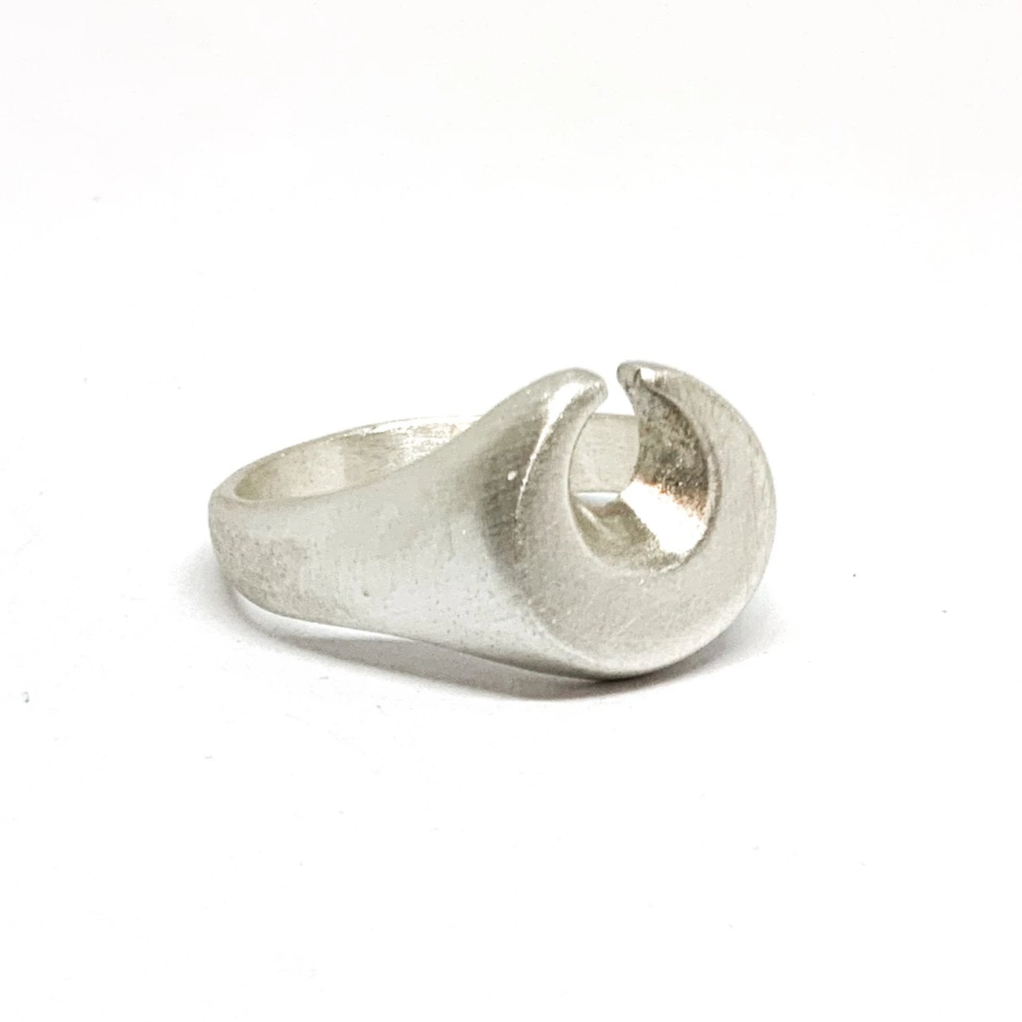 A silver ring featuring a brushed finish, handcrafted in the shape of a moon.