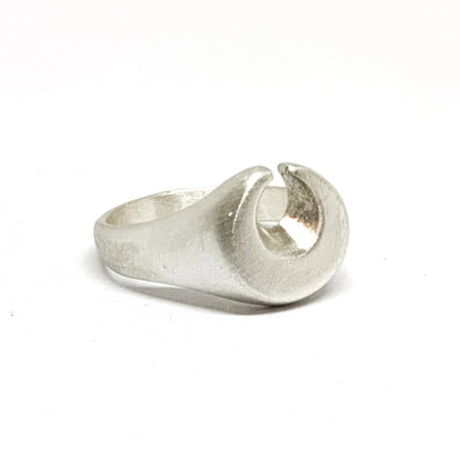 A silver ring featuring a brushed finish, handcrafted in the shape of a moon.