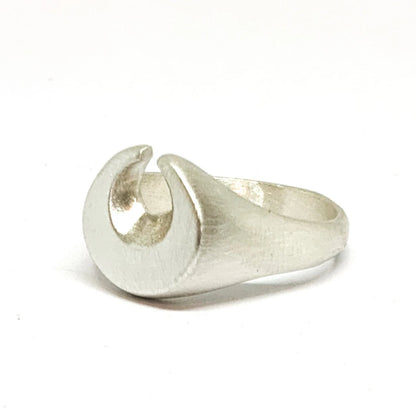 A silver ring featuring a brushed finish, handcrafted in the shape of a moon.