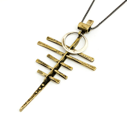 A silver-colored necklace with a pendant featuring a series of parallel lines and a circular ring, presented against a white background.