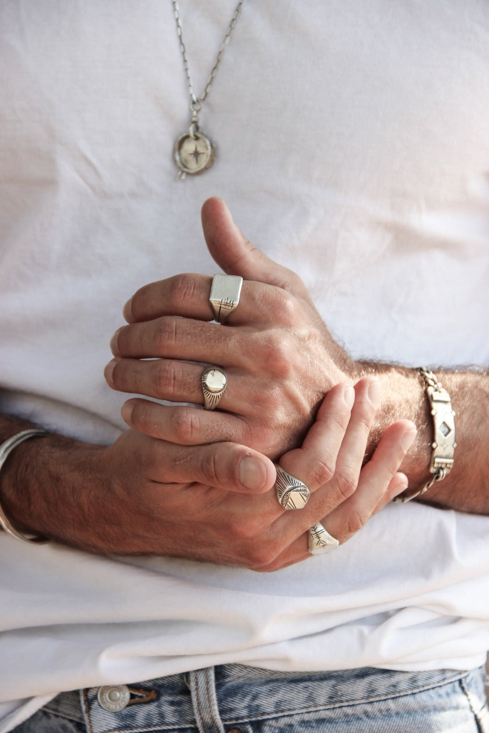 Men wearing silver shelly ganz rings: sun ring, nomad ring, maayan ring, carved memo ring and a silver bracelets