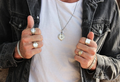 A silver signet ring with a geometric pattern on the top part, surrounded by a plain band.