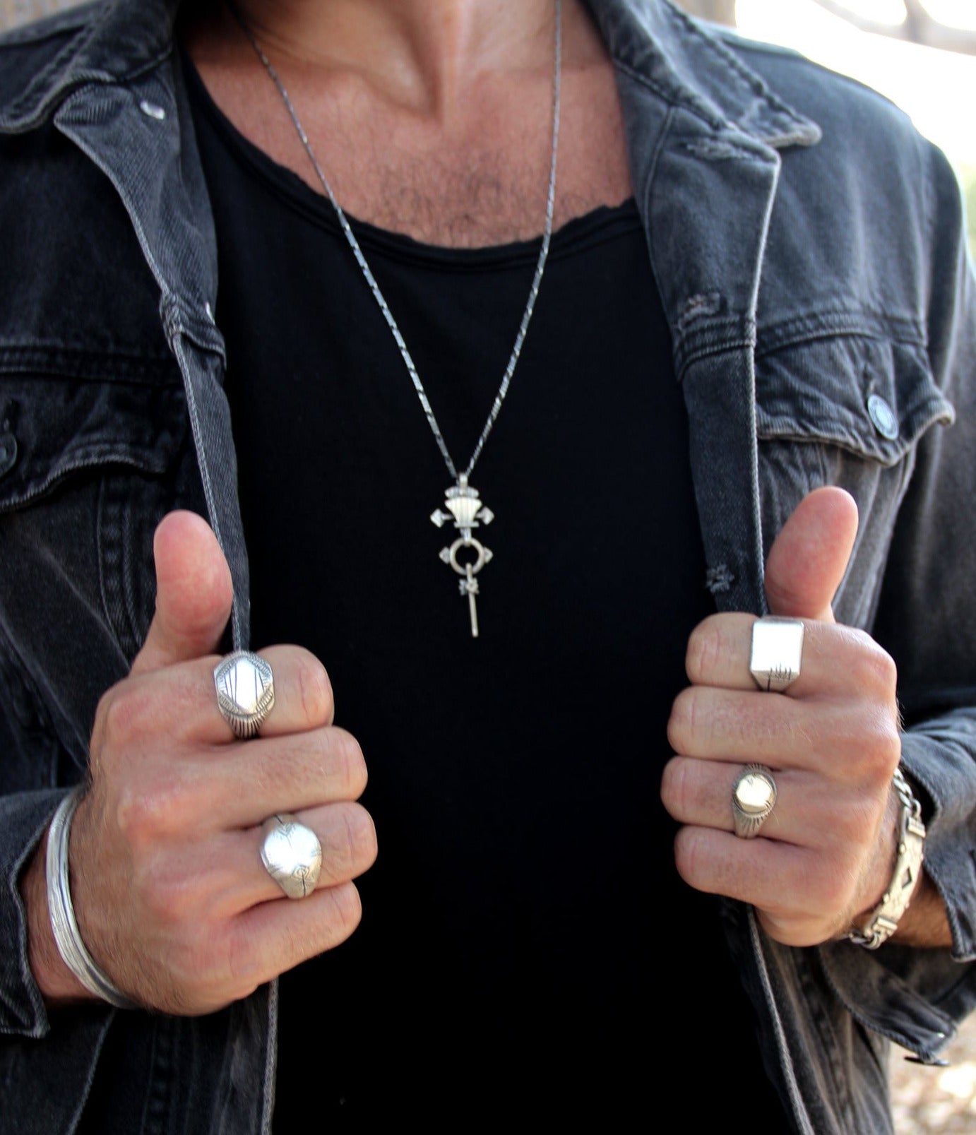 A silver signet ring with a geometric pattern on the top part, surrounded by a plain band.