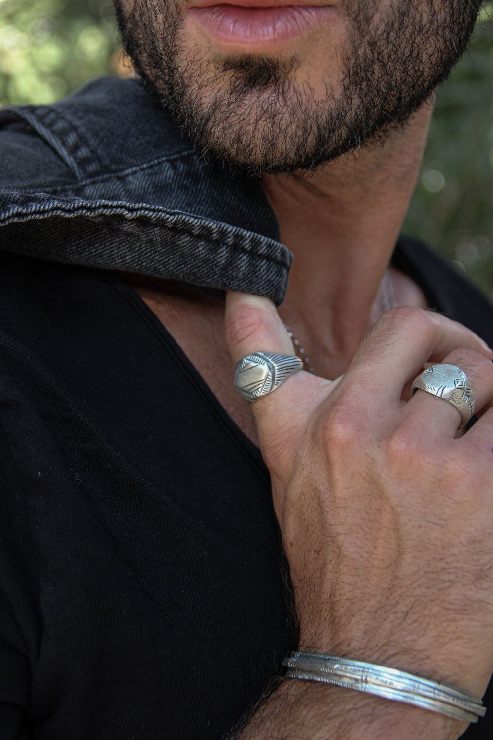 A silver signet ring with a geometric pattern on the top part, surrounded by a plain band.