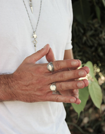A silver signet ring with a geometric pattern on the top part, surrounded by a plain band.