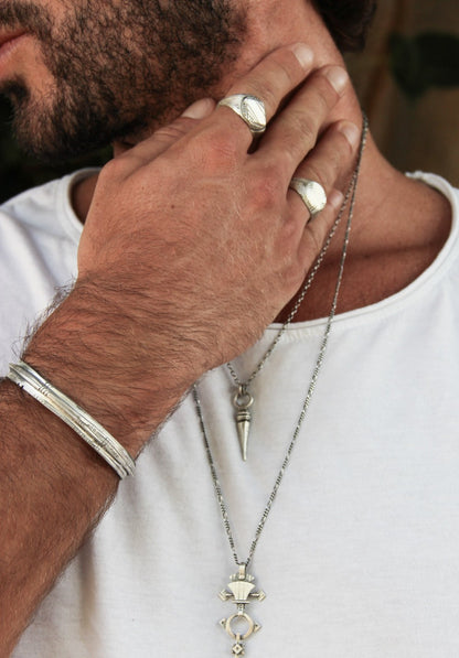 A sterling silver bracelet with an oxidized and brushed finish, featuring text on the bracelet surface.
