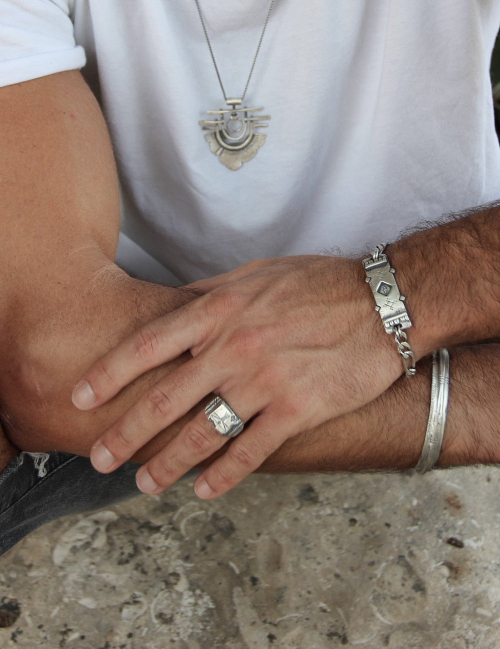 A silver ring with an oxidized and brushed finish, featuring an engraved design inspired by Florentine art, including figures and architectural elements.