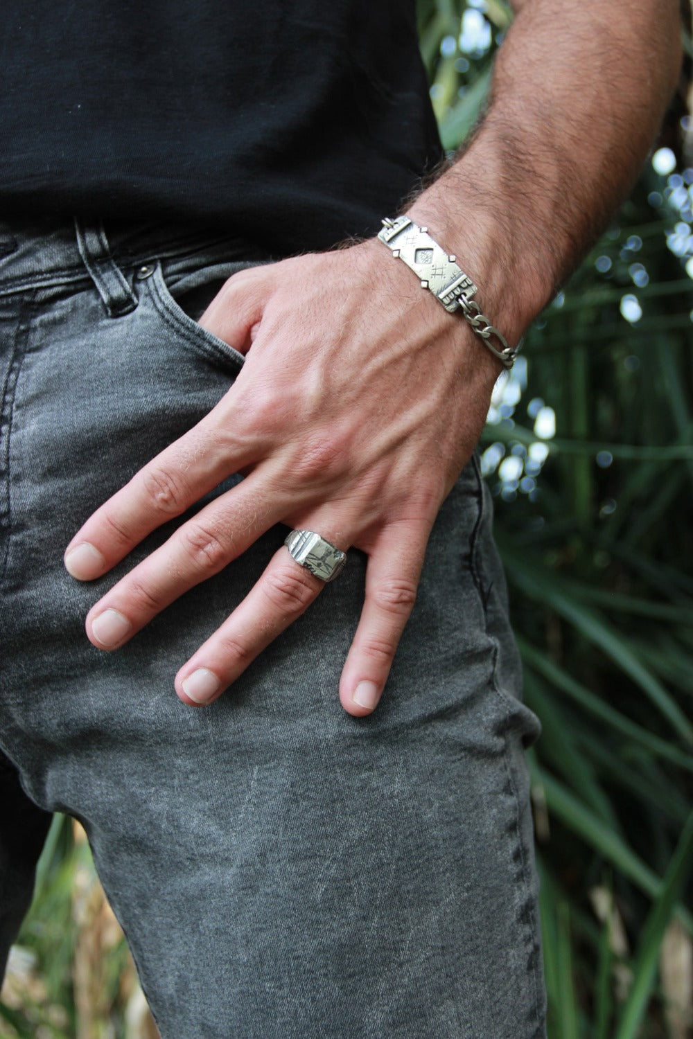 A silver ring with an oxidized and brushed finish, featuring an engraved design inspired by Florentine art, including figures and architectural elements.