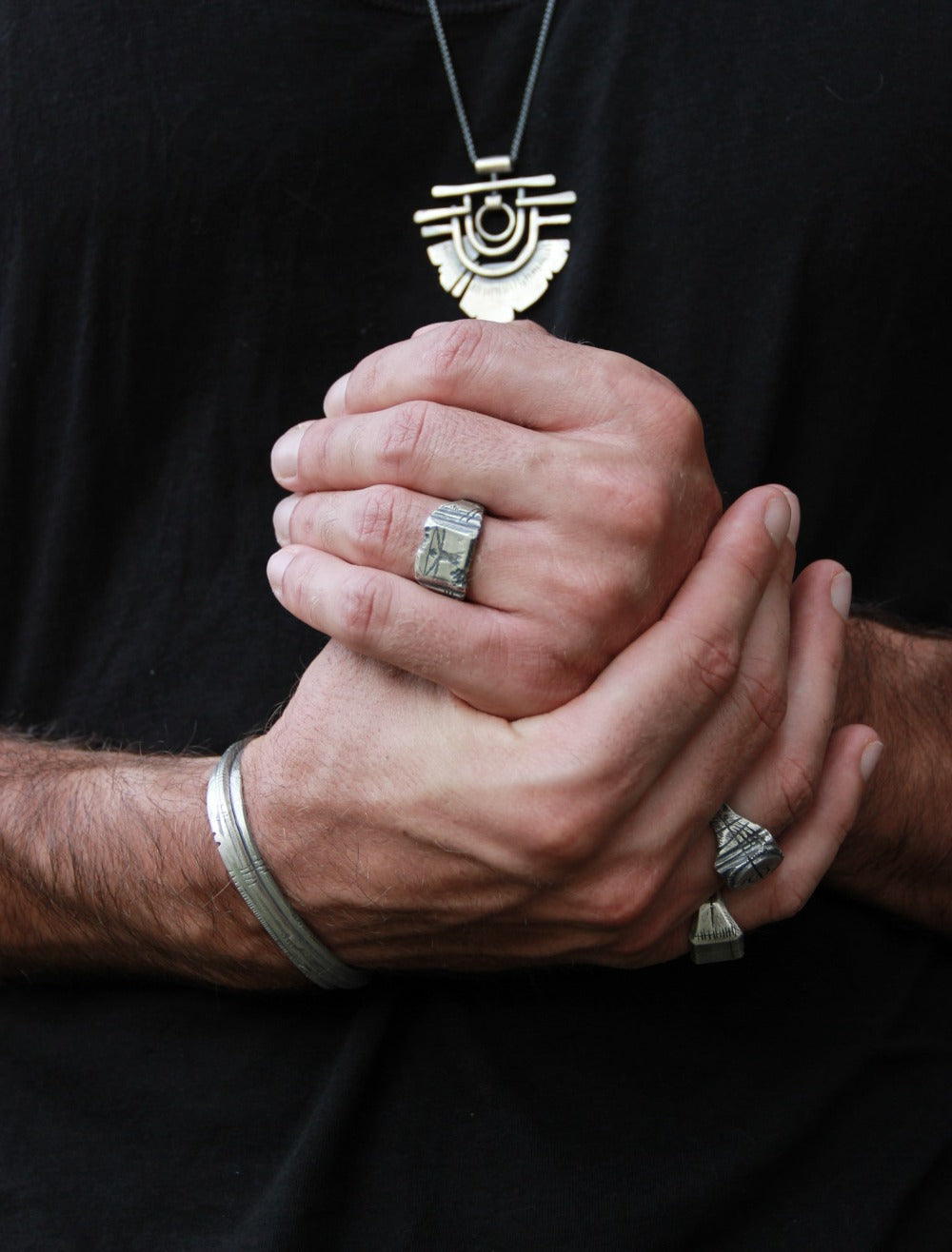 A silver ring with an oxidized and brushed finish, featuring an engraved design inspired by Florentine art, including figures and architectural elements.
